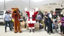 Seorang polisi Peru berpakaian seperti Santa Claus berteriak untuk memberikan hadiah kepada warga selama perayaan Natal di Huaycan, Lima, Peru (15/12/2015). (REUTERS/Janine Costa)