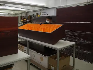 Seorang pekerja memindahkan peti mati kertas di pabrik LifeArt di Hong Kong pada Jumat, 18 Maret 2022. Hong Kong kehabisan peti mati selama wabah paling mematikan dari pandemi virus corona covid-19. (AP Photo/Kin Cheung)