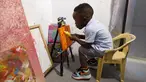 Ace-Liam Nana Sam Ankrah, yang akan berulang tahun ke dua pada bulan Juli, memamerkan tabung catnya di galeri seni ibunya di Accra, Ghana, pada 27 Mei 2024. (AP Photo/Misper Apawu)