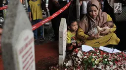 Seorang ibu sambil menggendong bayinya berziarah ke makam Presiden ketiga RI BJ Habibie di TMP Kalibata, Jakarta, Kamis (12/9/2019). Hingga sore hari, warga terus berdatangan ke TMP kalibata untuk dapat berkesempatan mendoakan almarhum BJ Habibie. (merdeka.com/Iqbal Nugroho)