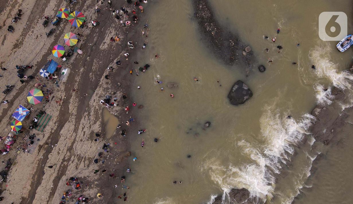 <p>Foto udara menunjukkan wisatawan berenang di aliran sungai Cipamingkis Kecamatan Sukamakmur, kabupaten Bogor, Jawa Barat, Kamis (5/5/2022). Warga memanfaatkan aliran sungai tersebut sebagai sarana hiburan Hari Raya Idul Fitri 1443 Hijriah. (merdeka.com/Imam Buhori)</p>