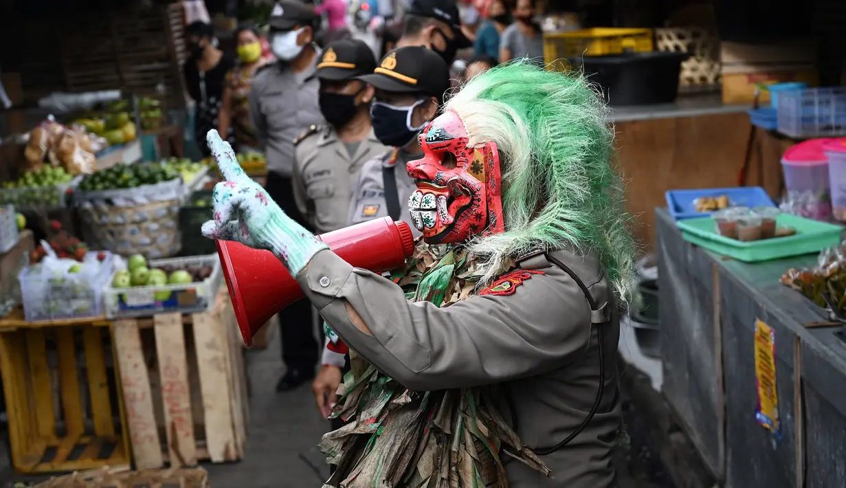Polisi mengenakan topeng menyeramkan yang disebut "Leak" saat sosialisasi langkah-langkah pencegahan COVID-19 di pasar tradisional di Kerobokan, Denpasar, Kamis (14/5/2020). Kegiatan itu untuk mengimbau masyarakat terus melakukan berbagai upaya pencegahan penyebaran COVID-19. (SONNY TUMBELAKA/AFP)