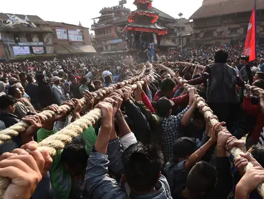 Umat Hindu Nepal menarik kereta kayu dewa Bhairava yang melewati kerumunan saat festival Bisket Jatra di Bhaktapur, Nepal (10/4). Festival ini diadakan untuk menandai Tahun Baru Nepal. (AFP Photo/Prakash Mathema)