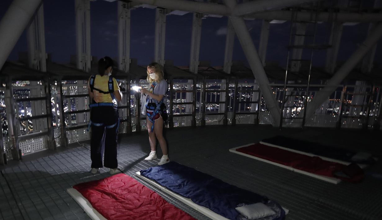Orang-orang saat menginap di tempat berkemah semalam di atap gedung pencakar langit di Seoul, Korea Selatan (7/8/2020). Menara Lotte World membuka area berkemah jarak sosial di atap menara dan tanah untuk orang-orang yang jenuh di cuaca musim panas dan Covid-19. (AP Photo/Lee Jin-man)