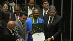 Pembalap Formula 1 Mercedes asal Inggris Lewis Hamilton (tengah) memegang gelar Warga Kehormatan Brasil, bersama Presiden Kamar Deputi Arthur Lira, kanan, di Brasilia, Brasil (7/11/2022). Juara F1 sebanyak tujuh kali, Lewis Hamilton, menjadi seorang pembalap Brazil pada Senin (7/11). (AP Photo/Eraldo Peres)