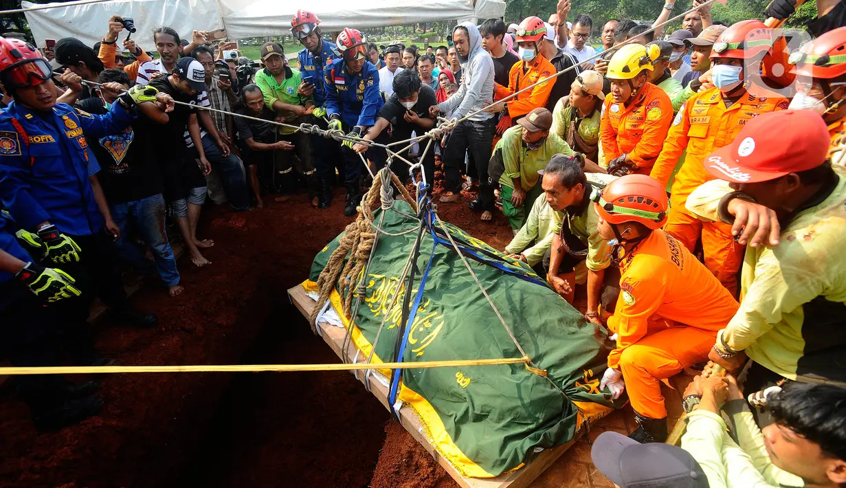 Petugas Basarnas dan Damkar memakamkan Moch Fajri Rifana (26), penderita obesitas berbobot 300 kilogram yang meninggal di Rumah Sakit Umum Pusat Nasional dr. Cipto Mangunkusumo di TPU Menteng Pulo, Jakarta, Kamis (22/6/2023). Pemakaman mempergunakan car lift dan alat tripod pengungkit jenazah. (merdeka.com/Arie Basuki)