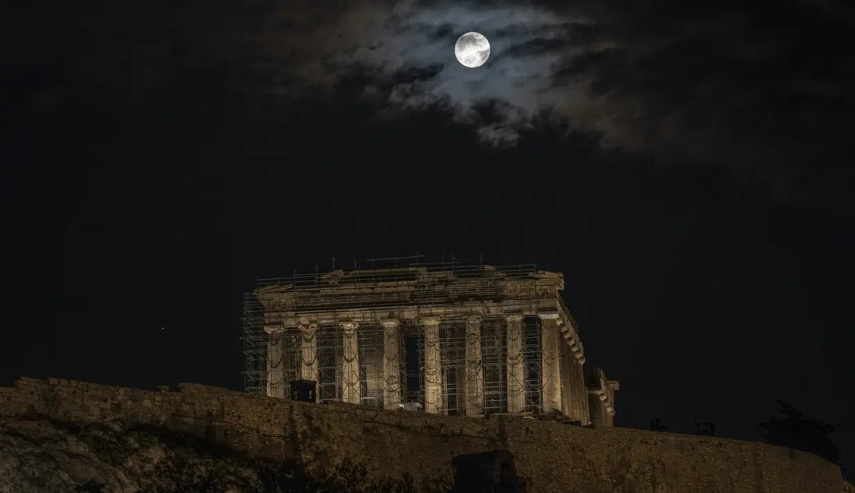 Bulan purnama terakhir tahun ini yang dikenal sebagai bulan dingin muncul di atas kuil kuno Parthenon saat hari mendung, di Athena, Yunani, Rabu (7/12/2022). Bulan purnama Desember sendiri dikenal sebagai Cold Moon atau Bulan Dingin. (AP Photo/Petros Giannakouris)
