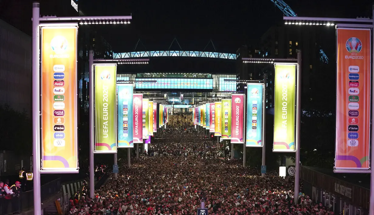 Fans Inggris merayakan di luar Stadion Wembley setelah Inggris lolos ke final Euro 2020 usai mengalahkan Denmark di London, Kamis (8/7/2021). Gol perpanjangan waktu Harry Kane memberi Inggris kemenangan 2-1 atas Denmark. (Zac Goodwin/PA via AP)