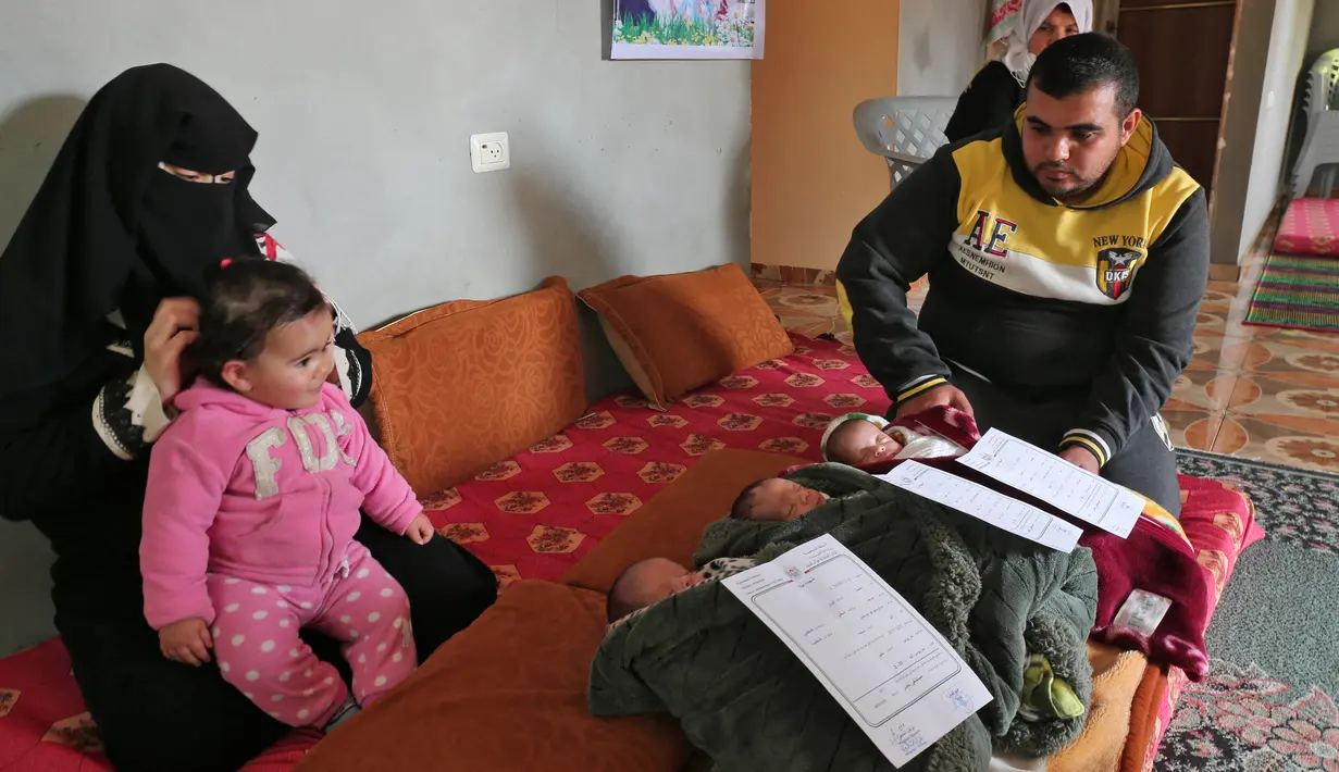 Pasangan Nidal dan Islam Al-Saiqli berpose dengan bayi kembar mereka, Jerusalem, Capital dan Palestine di Khan Yunis, Jalur Gaza, Jumat (2/2). Nama unik itu untuk memprotes Donald Trump yang mengklaim Yerusalem sebagai ibu kota Israel (SAID KHATIB/AFP)