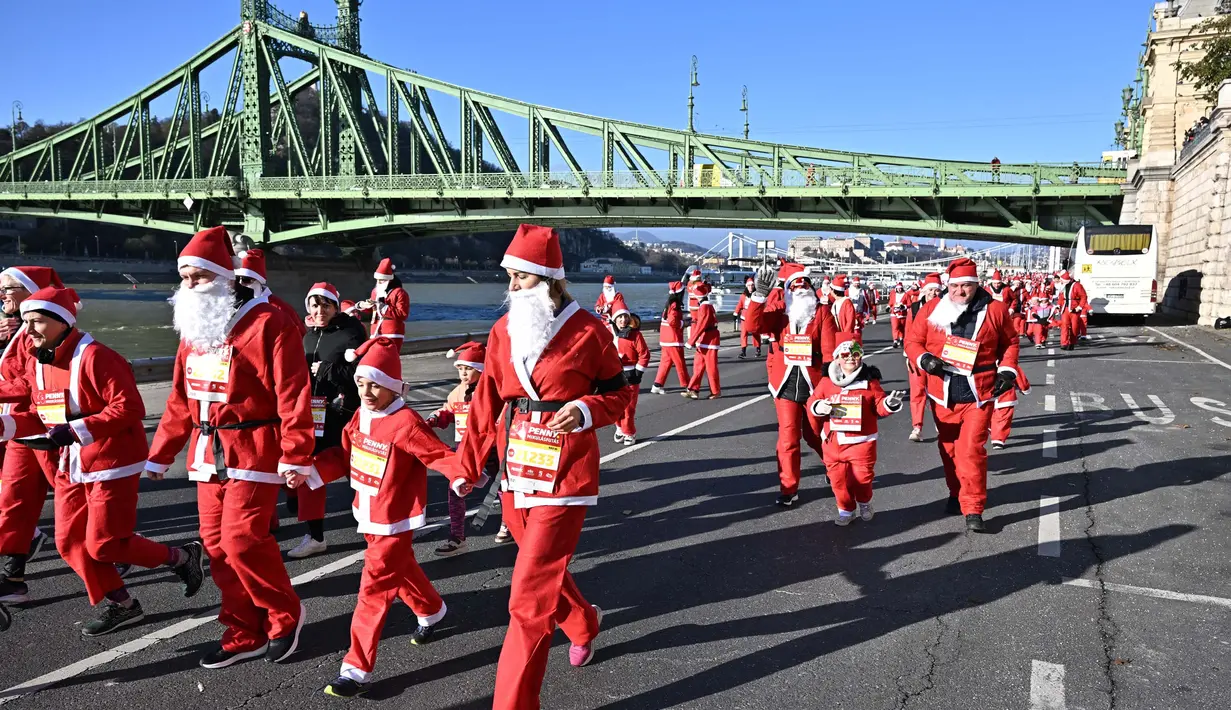 Orang-orang dengan kostum Sinterklas ikut serta dalam lomba lari tradisional menyambut Natal di tepi Sungai Danube di Budapest, Hungaria, pada 3 Desember 2023. (ATTILA KISBENEDEK/AFP)