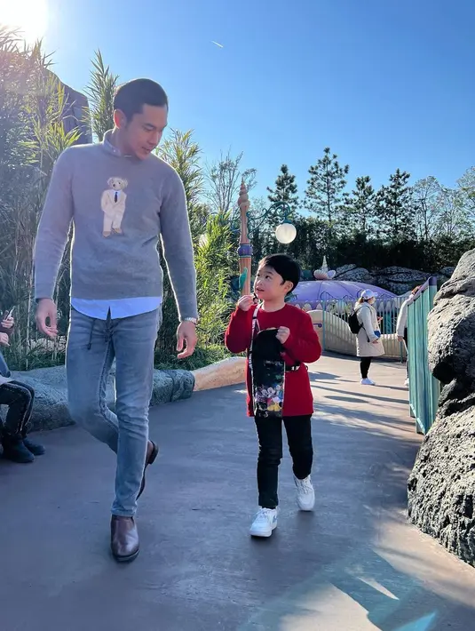 Harvey Moeis tampil serasi bersama Raphael Moeis mengenakan sweater. Harvey mengenakan kemeja biru yang ditumpuknya dengan sweater abu-abu bercorak teddy yang gemas, dipadunya dengan celana jeans. Sedangkan sang anak mengenakan sweater merah dan celana panjang hitam, serta sneakers putih. [Foto: Instagram/raphaelmoeis]