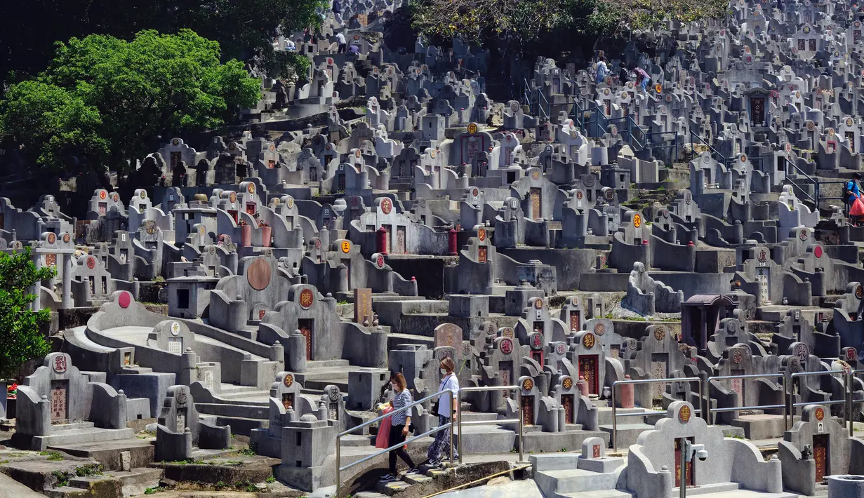 Orang-orang yang mengenakan masker berjalan di pemakaman saat Festival Ching Ming atau Hari Sapu Makam di Hong Kong, Selasa (5/4/2022). Ribuan warga Hong Kong memberi hormat kepada leluhur dan kerabat mereka selama festival tahunan ini. (AP Photo/Vincent Yu)