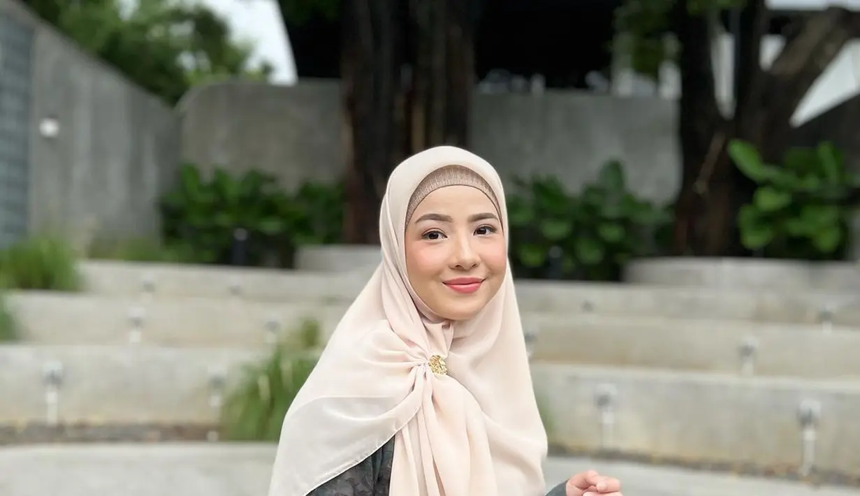 Ciptakan tampilan yang elegan dengan padu padan tiered dress warna gelap dan hijab warna cream cerah. [Foto: IG/natasharizkynew].