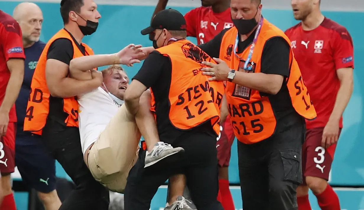 Petugas menangkap penyusup lapangan selama pertandingan sepak bola Perempatfinal UEFA EURO 2020 antara Swiss melawan Spanyol yang berlangsung di Stadion Krestovsky, Saint Petersburg, Rusia pada 2 Juli 2021. (AFP/Pool/Maxim Shemetov)