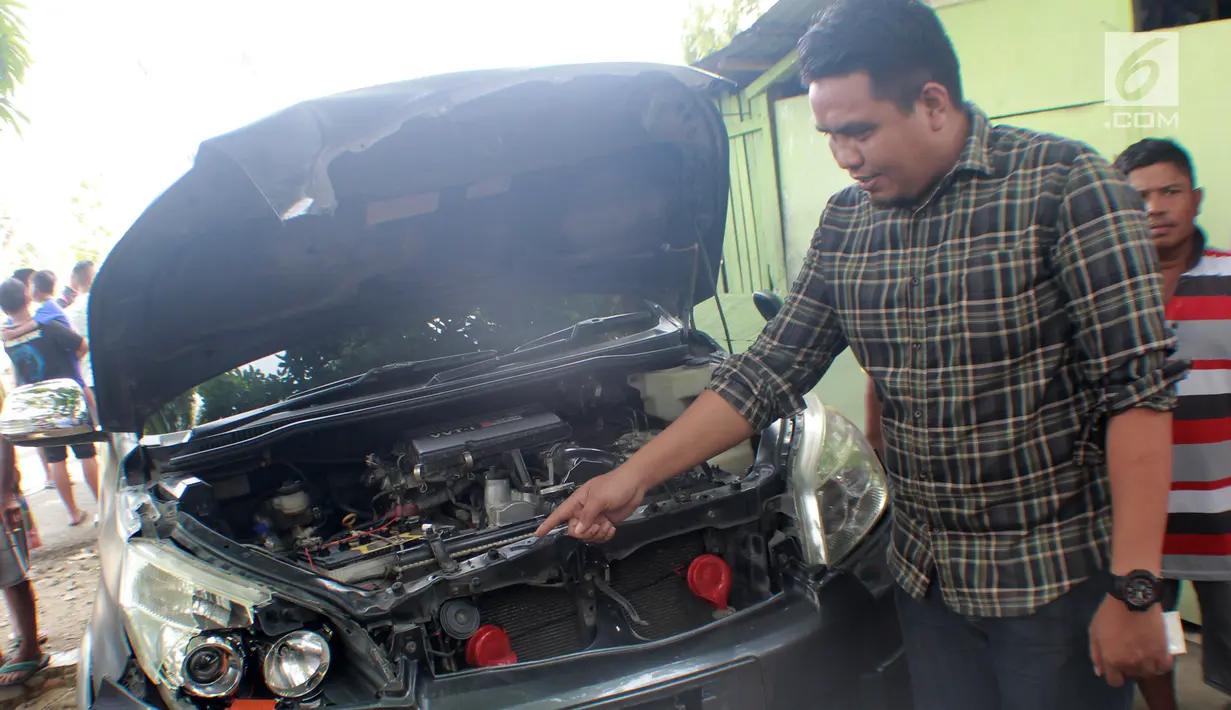 Seorang pria menunjukkan mobil yang rusak usai tertimpa pohon berumur puluhan tahun di Jalan Trans Sulawesi, Limboto, Gorontalo, Senin, (21/1). Tidak ada korban jiwa dalam kejadian tersebut. (Liputan6.com/Arfandi Ibrahim)