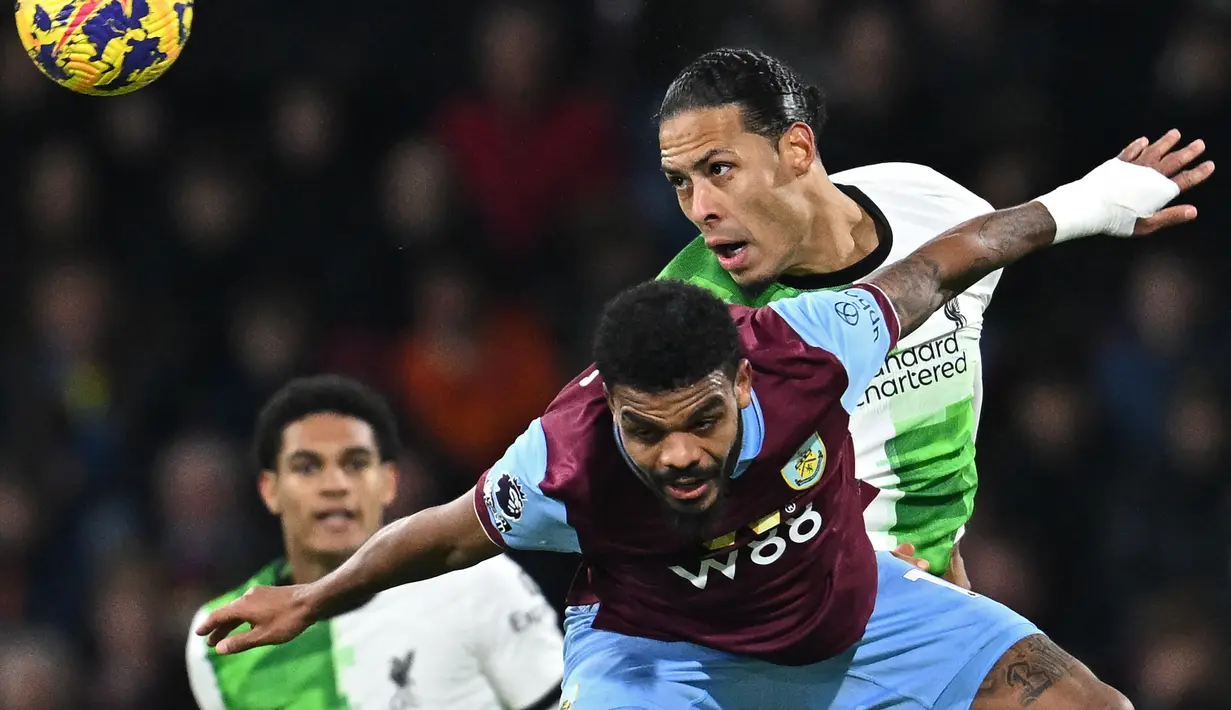 Bek Liverpool #04 Virgil van Dijk (kanan) bersaing dengan striker Burnley #17 Lyle Foster (tengah) pada pertandingan pekan ke-19 Premier League 2023/2024 di Turf Moor, Rabu (27/12/2023) dini hari WIB. (Paul ELLIS / AFP)