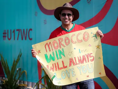 Suporter Maroko, Mohammad Aziz Mrabat berpose dengan membentangkan poster bertuliskan "Maroko, menang atau kalah aku tetap mencintaimu" menjelang laga kedua Grup A Piala Dunia U-17 2023 antara Timnas Maroko U-17 melawan Timnas Ekuador U-17 di Stadion Gelora Bung Tomo (GBT), Surabaya, Senin (14/11/2023). (Bola.com/Bagaskara Lazuardi)
