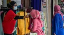 Pekerja memeriksa suhu seorang wanita Muslim, sebagai tindakan pencegahan penyebaran Covid-19 sebelum memasuki toko yang menjual pakaian budaya Malaysia atau baju melayu dan baju kurung menjelang Idul Fitri yang menandai berakhirnya bulan suci Ramadan di Kuala Lumpur (13/5/2020). (AFP/Mohd Rasfan)