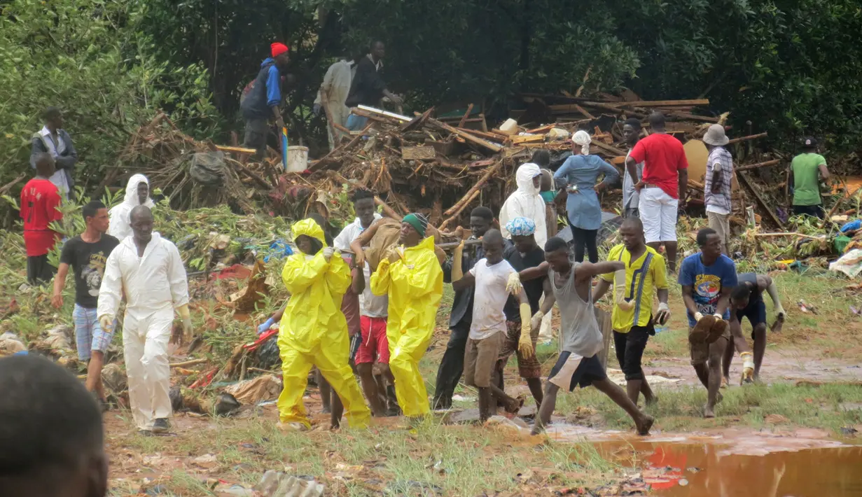 Petugas penyelamat membawa mayat korban dari lokasi tanah longsor di Regent, sebelah timur Freetown, Sierra Leone, (14/8). Bencana ini terjadi saat penduduk tengah tidur sehingga banyak yang terjebak di dalam rumah. (AP Photo / Manika Kamara)