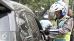 Petugas menilang pengendara mobil yang melanggar aturan pembatasan kendaraan sistem ganjil genap di kawasan Sudirman, Jakarta, Selasa (30/8). Hari ini resmi diberlakukan denda bagi pelanggar aturan sistem ganjil genap. (Liputan6.com/Yoppy Renato)