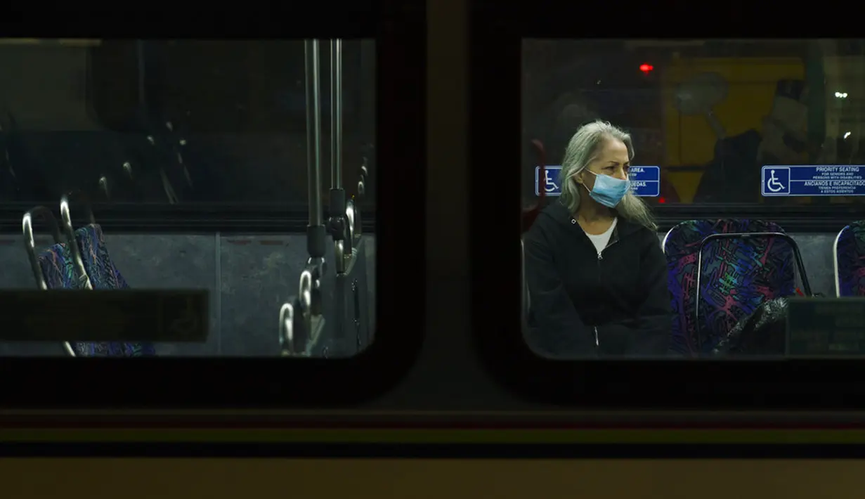 Seorang komuter mengenakan masker saat duduk dalam bus di Los Angeles, California, Amerika Serikat, Kamis (12/11/2020). California menjadi negara bagian kedua selain Texas yang mencatat 1 juta kasus infeksi COVID-19. (AP Photo/Jae C. Hong)