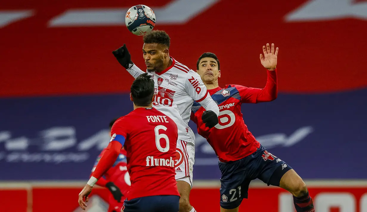 Striker Brest, Steve Mounie (tengah) melompat di antara dua pemain Lille, Jose Fonte (kiri) dan Benjamin Andre dalam laga lanjutan Liga Prancis 2020/21 pekan ke-25 di The Stade Pierre Mauroy, Lille, Minggu (14/2/2021). Brest bermain imbang 0-0 dengan Lille. (AP/Michel Spingler)