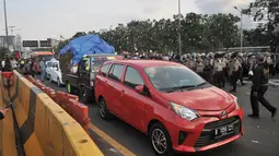 Sejumlah kendaraan berusaha melintas di antara massa pengunjuk rasa yang memasuki Tol Dalam Kota dekat Gedung DPR,  Jakarta, Senin (30/9/2019). Kendaraan yang melintasi terjebak bentrokan antara massa dan polisi yang terjadi di dua sisi sehingga terpaksa berputar arah. (merdeka.com/Iqbal S Nugroho)