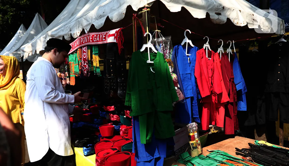 Pengunjung melihat stan pedagang aksesoris pakaian khas Betawi merapikan barang dagangannya dalam Lebaran Tenabang 2022 di kawasan Tanah Abang, Jakarta, Sabtu (4/6/2022). Kegiatan yang menampilkan berbagai kesenian Betawi, makanan tradisional, perlombaan, dan bazar UMKM itu mengangkat tema KolaborAksi. (Liputan6.com/Angga Yuniar)