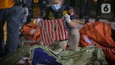 Petugas kepolisian memeriksa pakaian korban kecelakaan pesawat Sriwijaya Air nomor penerbangan SJ 182 rute Jakarta-Pontianak pada hari ketujuh operasi SAR pesawat tersebut di JICT II Tanjung Priok, Jakarta Utara, Jumat (15/1/2021). (Liputan6.com/Faizal Fanani)