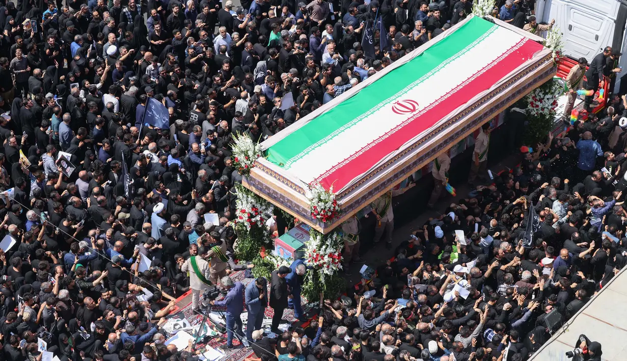 Kerumunan besar warga Iran terlihat memadati jalan-jalan di ibu kota Teheran untuk mengikuti prosesi pemakaman Presiden Ebrahim Raisi yang meninggal dunia dalam kecelakaan helikopter pada Minggu (19/5/2024). (ATTA KENARE/AFP)