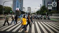 Sejumlah pekerja berjalan melintas pelican cross di kawasan Jalan Sudirman, Jakarta, Selasa (2/11/2021). Sektor non-esensial kini boleh mempekerjakan hingga 75 persen karyawannya dari kantor. Sebelumnya, angka ini dibatasi hingga 50 persen. (Liputan6.com/Faizal Fanani)