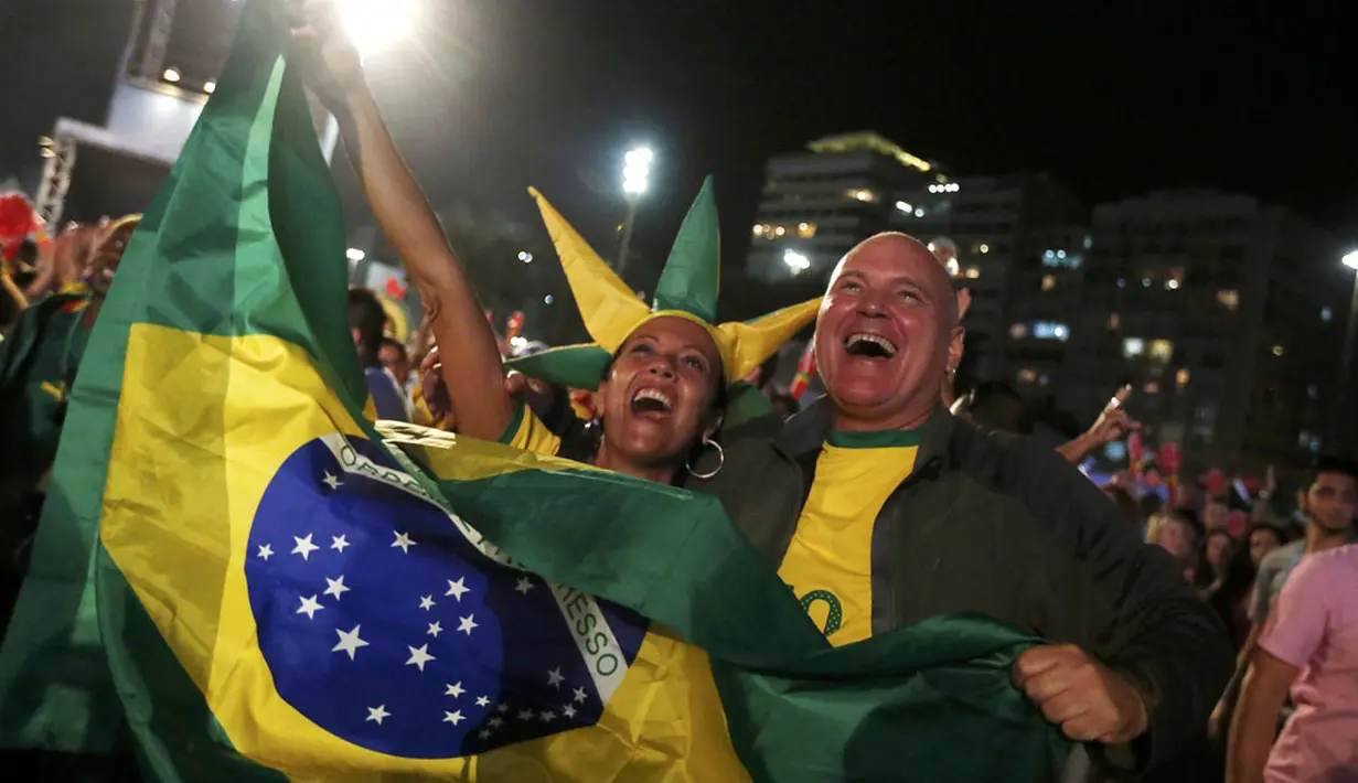 Di pantai Copacabana, Rio de Janeiro, (23/6/2014), warga Brasil bersorak merayakan keberhasilan tim Samba lolos ke fase knock out Piala Dunia 2014. (REUTERS/Pilar Olivares) 