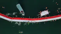 Para perenang dari Makassar Watersports Community dan klub-klub renang serta personel Kantor Pencarian dan Pertolongan dan Kepolisian Perairan berpartisipasi dalam kegiatan pembentangan bendera Merah Putih dari Dermaga Kayu Bangkoa, yang dilanjutkan dengan pengarakan bendera sampai ke Pulau Gusung. (Muchtamir ZAIDE/AFP)