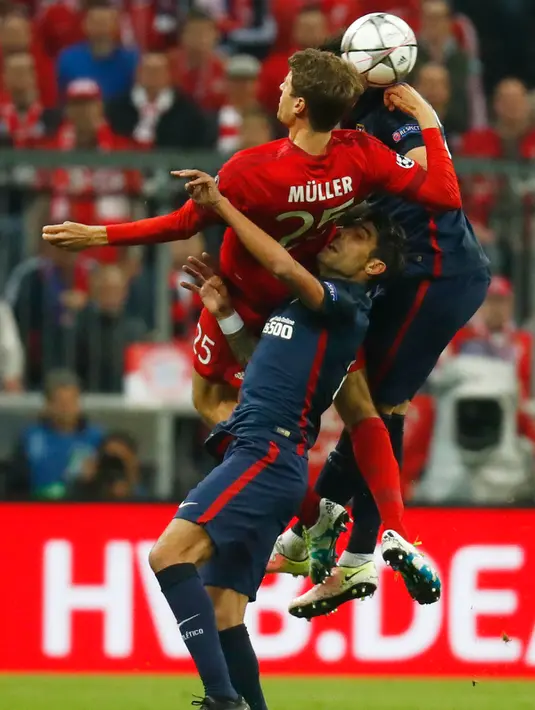 Penyerang Muenchen, Thomas Muller berebut bola dengan dua pemain Atletico Madrid di leg kedua semifinal Liga Champions di Allianz Arena (4/5). Meski kalah 2-1 dari Munchen, Atletico melaju ke final dengan aggregat gol tandang. (Reuters/Kai Pfaffenbach)