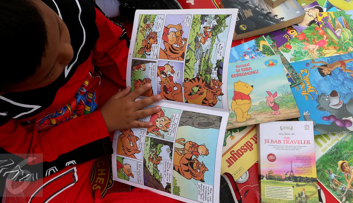Seorang anak membaca buku di Kawasan Bundaran HI saat berlangsungnya Hari Bebas Kendaraan Bermotor, Jakarta, Minggu (2/4). Kegiatan ini dilakukan sebagai ajakan kampanye "Budayakan Membaca dari Desa untuk Indonesia". (Liputan6.com/Johan Tallo)