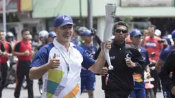 Pevoli legendaris Indonesia, Pascal Wilmar, berlari saat pawai obor Asian Games XVIII di Palembang, Sumatra Selatan, Sabtu (4/8/2018). Sebanyak 53 kota di Indonesia akan dilalui oleh obor Asian Games. (Bola.com/Reza Bachtiar)