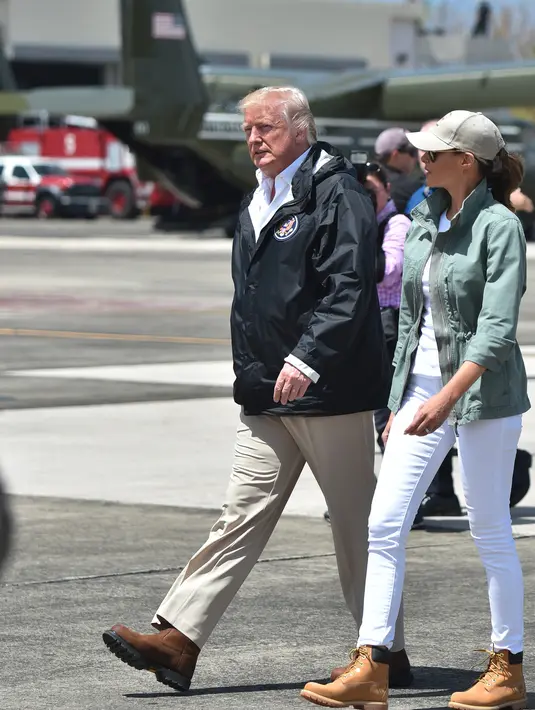 Presiden AS, Donald Trump dan Ibu Negara AS, Melania Trump setibanya di Luis Muñiz Air National Guard Base, Puerto Rico, Selasa (3/10). Dalam kunjungannya, Melania menggunakan sepatu boot kerja untuk digunakan meninjau daerah bencana. (HECTOR RETAMAL/AFP)