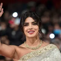 Aktris Priyanka Chopra menyapa penggemarnya saat tiba menghadiri Festival Film Internasional Marrakech ke-18 di Jemaa El Fnaa, Marrakech (5/12/2019). Priyanka Chopra tampil cantik memesona mengenakan busana sari emas dan brokat perak denga dengan kalung emas di lehernya. (AFP/Fadel Senna)
