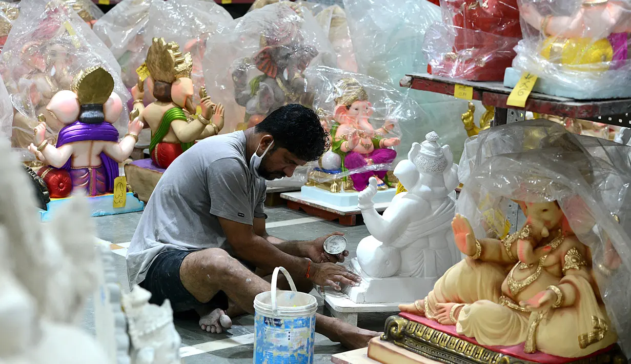 Seorang perajin mengerjakan pembuatan patung Dewa Ganesha di sebuah bengkel di Mumbai, India, 24 Agustus 2021. Pembuatan patung dewa Hindu berkepala gajah tersebut dilakukan jelang Festival Ganesh Chaturthi. (SUJIT JAISWAL/AFP)