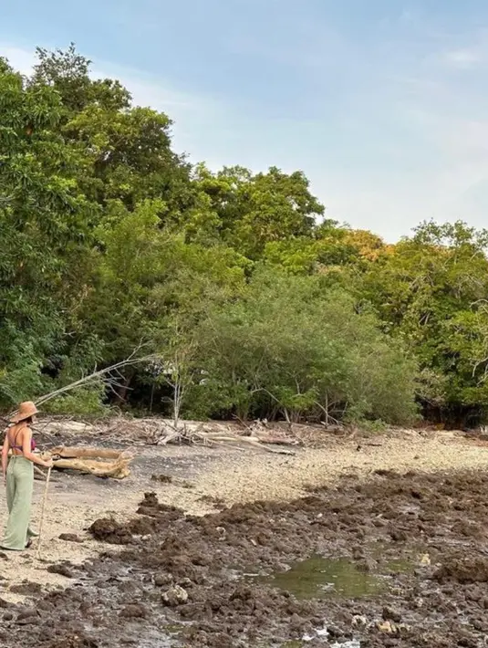 Menyusuri jalan di sekitar pantai, Pevita tampil santai dengan bikininya yang dipadukan long pants hijau.
