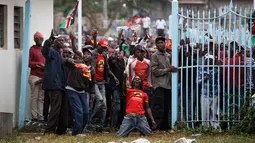 Pendukung Presiden Uhuru Kenyatta berdiri di depan gerbang saat pelatikan Presiden Kenya Uhuru Kenyatta di Nairobi, Kenya (28/11). Para pendukung ini memaksa masuk untuk mengikuti pelantikan Presiden Kenya Uhuru Kenyatta. (AP Photo / Ben Curtis)