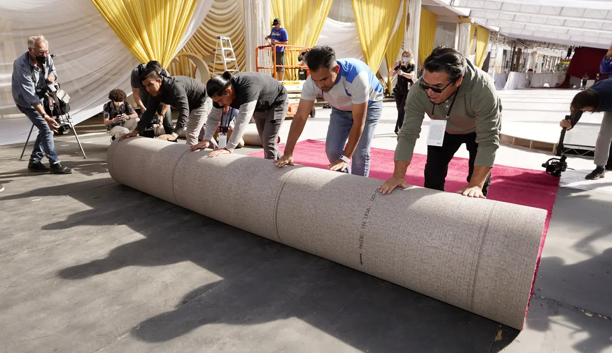 Anggota kru menggelar karpet merah untuk Academy Awards ke-94 atau disebut juga piala Oscar di luar Teater Dolby, Los Angeles, Rabu (23/3/2022). Ajang penghargaan Piala Oscar ke-94 akan diadakan pada Minggu, 27 Maret 2022 di Dolby Theatre Hollywood. (AP Photo/Chris Pizzello)