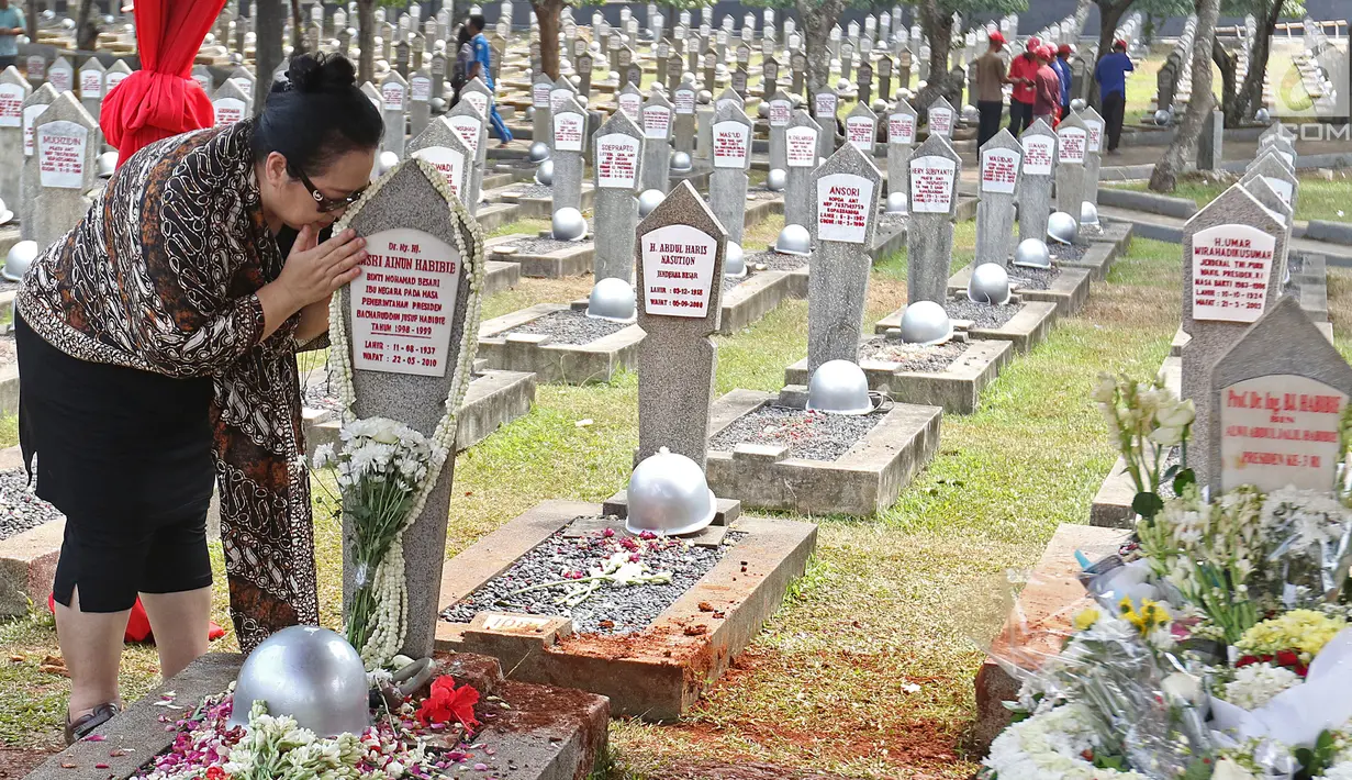 Warga mencium batu nisan di makam Hasri Ainun Besari yang bersebelah dengan makam sang suami, Presiden ke-3 RI BJ Habibie di TMP Kalibata, Jakarta, Jumat (13/9/2019). Sesuai permintaannya semasa hidup, BJ Habibie dimakamkan bersebelahan dengan mendiang istrinya Ainun. (Liputan6.com/Herman Zakharia)