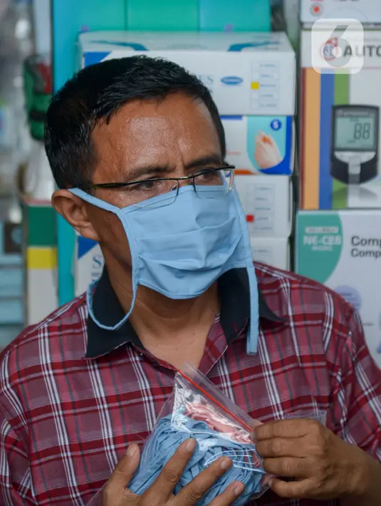 Seorang pria membawa sebungkus masker di Pasar Pramuka, Jakarta Timur, Rabu (4/3/2020). Polda Metro Jaya menggelar sidak di Pasar Pramuka untuk menyikapi lonjakan harga dan kelangkaan masker di pasaran terkait virus corona atau COVID-19. (merdeka.com/Imam Buhori)
