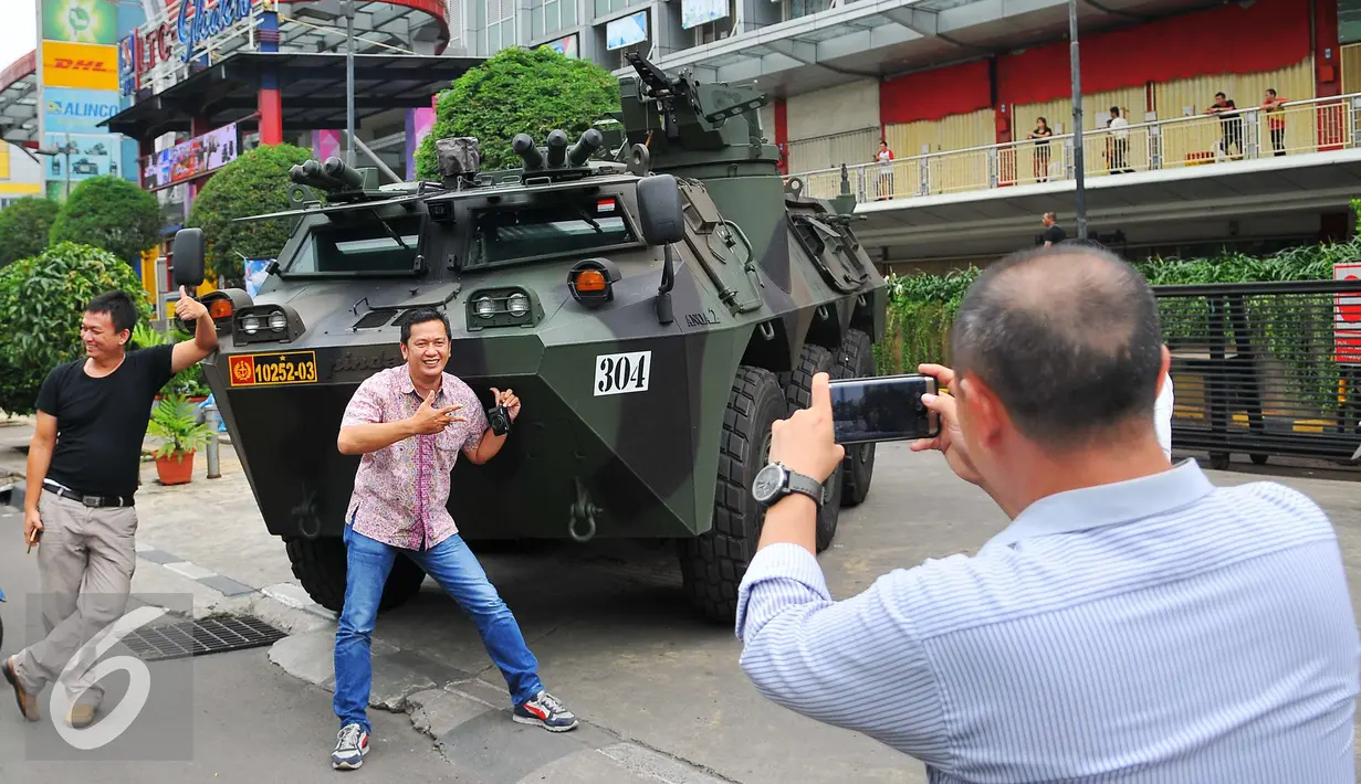 Sejumlah warga melakukan selfie dengan latar belakang Panser Anoa milik TNI di LTC Glodok, Jakarta, Jumat (4/11). Pengamanan ini merupakan bentuk kerja sama antara TNI-Polri dalam menjaga keamanan terkait demo bela islam . (Liputan6.com/Angga Yuniar)