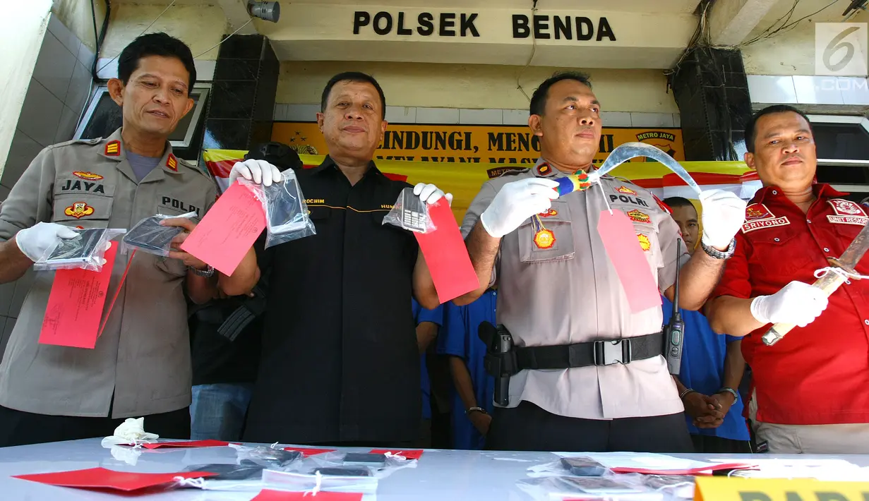 Polisi menunjukkan barang bukti celurit dan handphone di Mapolsek Benda, Tangerang, Banten, Senin (19/11). Polisi menangkap otak pelaku kejahatan spesialis handphone dan tiga tersangka lainnya. (Liputan6.com/Fery Pradolo)