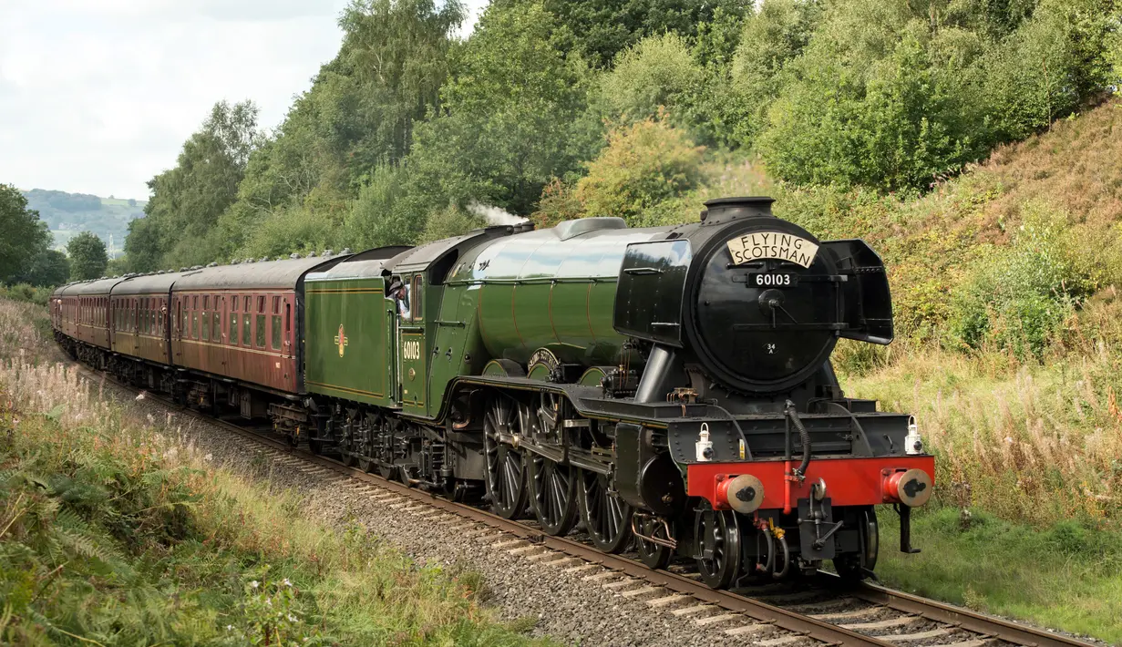 Lokomotif uap Flying Scotsman berjalan di sepanjang jalur East Lancashire Railway melalui stasiun kereta Burrs Country Park, Inggris, 5 September 2018. Kereta uap itu masih menggunakan mesin kuno berjenis A Class 60103 tahun 1923. (OLI SCARFF/AFP)