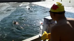 Dua perenang es berenang di danau yang membeku pada hari musim dingin di Beijing (6/1/2021). Berenang di musim dingin adalah kegiatan olahraga yang jarang dijumpai kecuali di beberapa negara dengan musim dingin yang cukup panjang. (AFP/Wang Zhao)