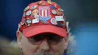 Seorang suporter Stoke City mengenakan topi dengan hiasan pin dari berbagai klub saat menonton timnya melawan Tottenham Hotspur pada lanjutan Liga Inggris di Stadion Britannia, Stoke, Selasa (19/4/2016) dini hari WIB. (AFP/Oli Scarff)