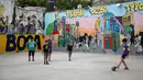 Anak-anak bermain sepak bola di taman bermain di lingkungan La Boca, ibu kota Argentina, Buenos Aires pada 27 November 2018. Bangunan di daerah ini sangat berwarna dengan berbagai warna cerah seperti melihat pelangi. (Ludovic MARIN / AFP)